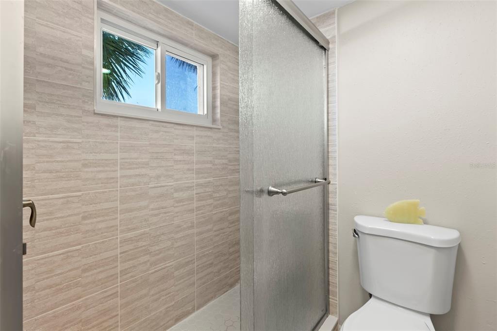 8911 Blind Pass Road, Unit 214 St. Pete Beach, FL 33706 - Photo 14 of 35 a bathroom with a toilet and a shower