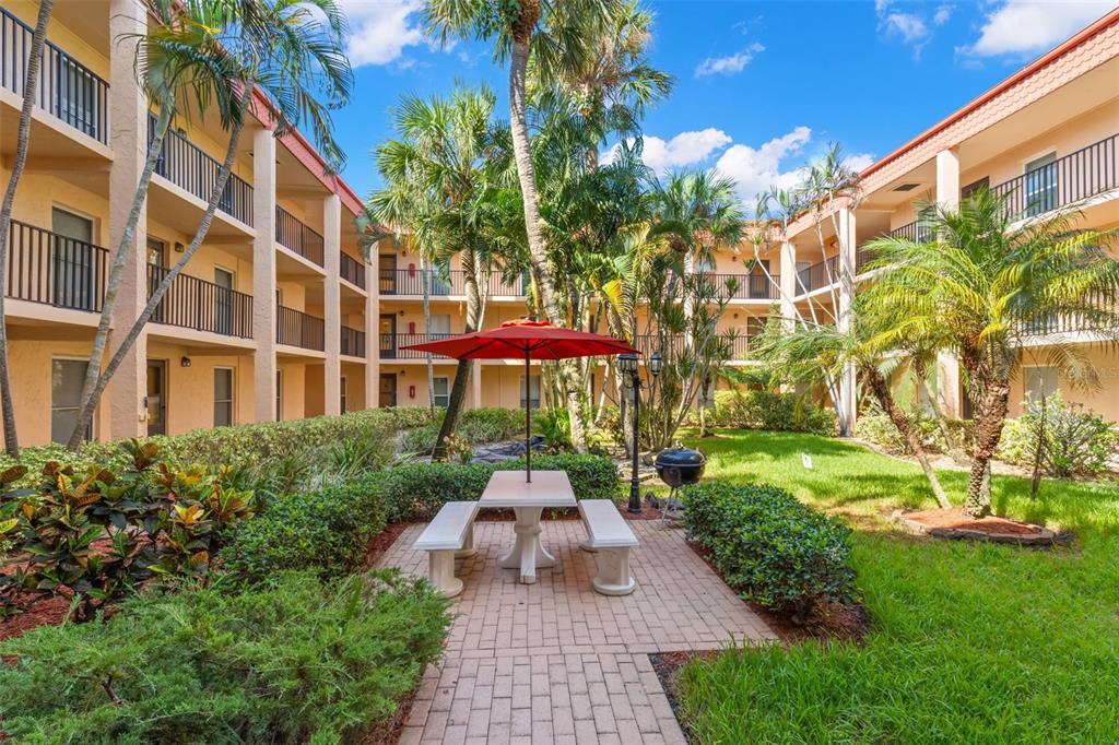 8911 Blind Pass Road, Unit 214 St. Pete Beach, FL 33706 - Photo 20 of 35 a view of a patio with couches table and chairs and potted plants