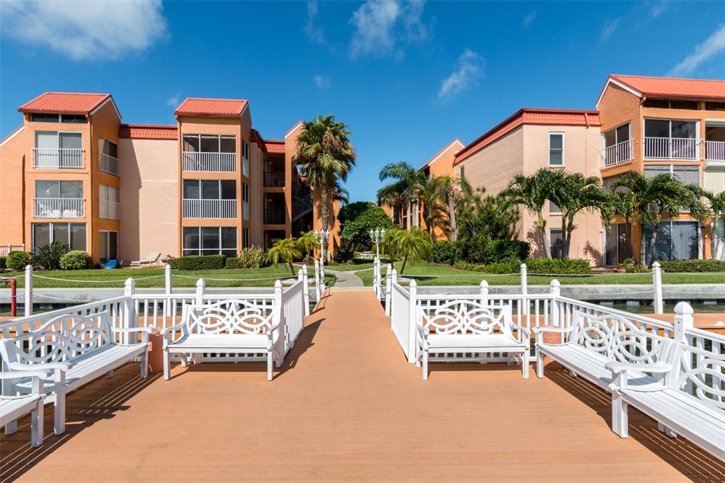 8911 Blind Pass Road, Unit 214 St. Pete Beach, FL 33706 - Photo 31 of 35 a view of an outdoor space with swimming pool and trees in the background