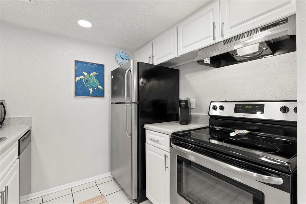 8911 Blind Pass Road, Unit 214 St. Pete Beach, FL 33706 - Photo 10 of 35 a metallic refrigerator freezer sitting inside of a kitchen