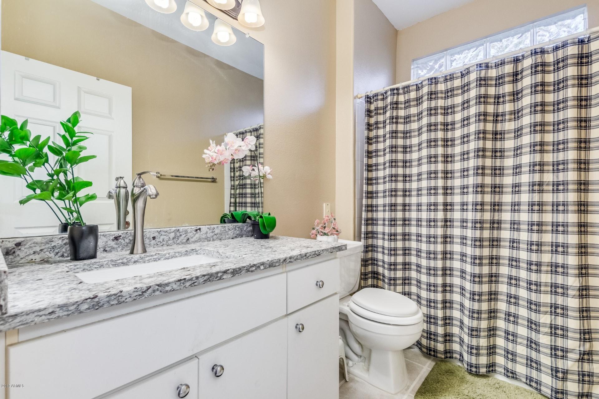 9550 East Thunderbird Road, Unit 252 Scottsdale, AZ 85260 - Photo 11 of 21 a bathroom with a granite countertop sink a toilet a mirror and shower