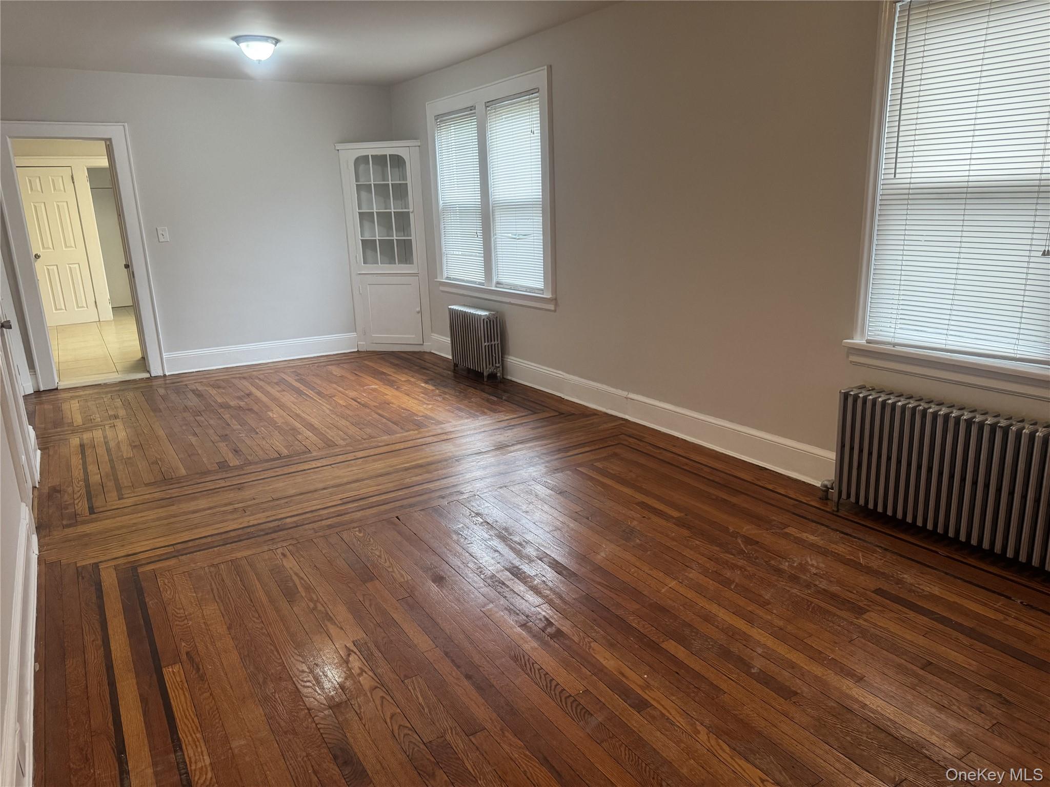 267 Schenck Avenue, Unit # RIGHT Great Neck, NY 11021 - Photo 4 of 8 Unfurnished room featuring dark hardwood / wood-style flooring and radiator