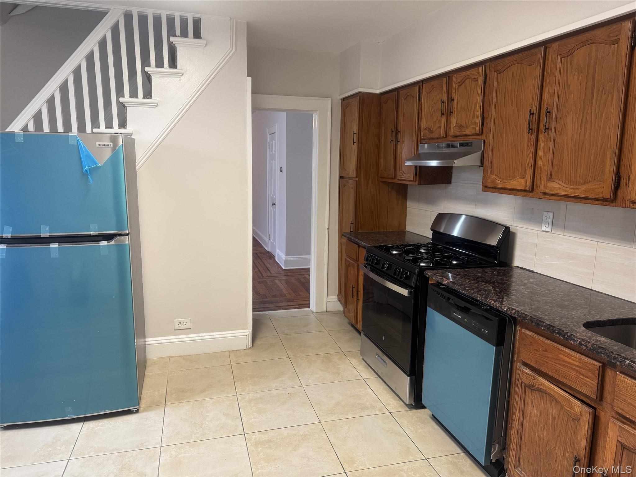 267 Schenck Avenue, Unit # RIGHT Great Neck, NY 11021 - Photo 6 of 8 Kitchen featuring dark stone countertops, decorative backsplash, light tile patterned floors, and stainless steel appliances