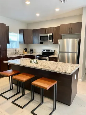 a kitchen with stainless steel appliances granite countertop a stove a sink a microwave a refrigerator and cabinets