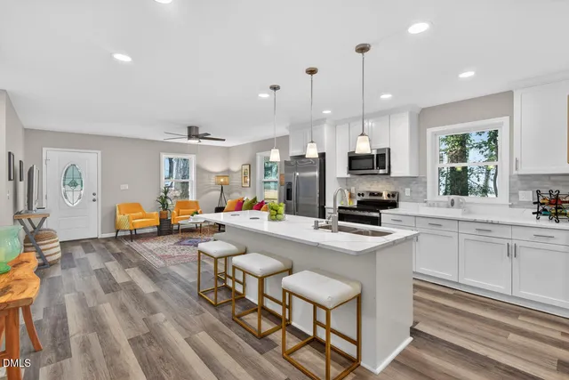 a kitchen with stainless steel appliances granite countertop a stove top oven a sink dishwasher a dining table and chairs with wooden floor