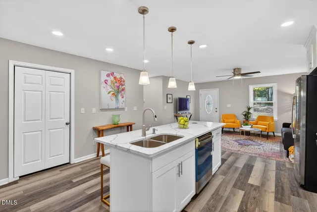 a kitchen that has a lot of cabinets a sink and wooden floor