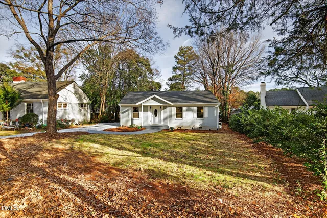 a view of a pathway of a house with wooden fence and large trees