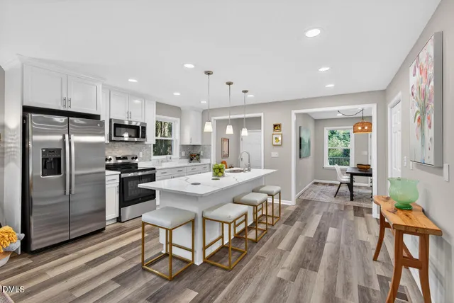 a kitchen with stainless steel appliances a dining table chairs stove refrigerator and cabinets