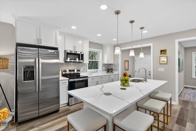 a kitchen with a refrigerator a stove a sink a dining table and chairs