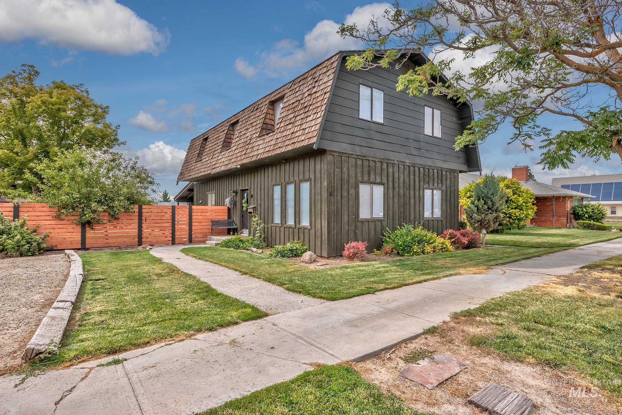 Gambrel-style residence featuring a dark-stained vertical board exterior and a wood-shingle roof