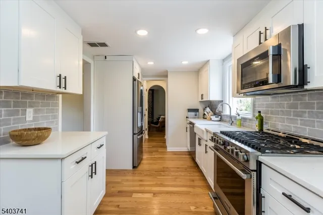 a kitchen with stainless steel appliances granite countertop a stove a sink and a microwave