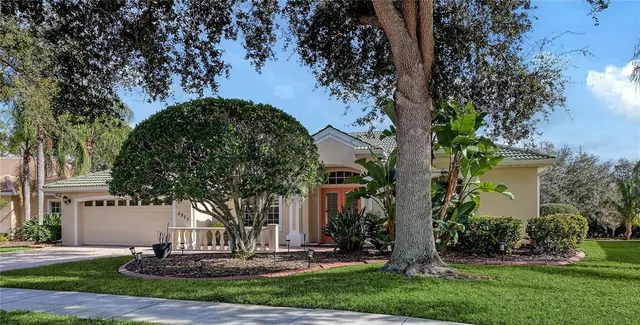 a front view of a house with garden and trees