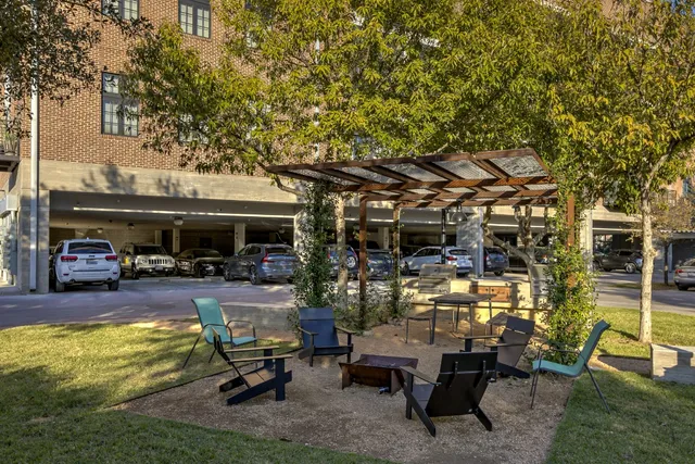 a view of a patio with table and chairs under an umbrella with large trees