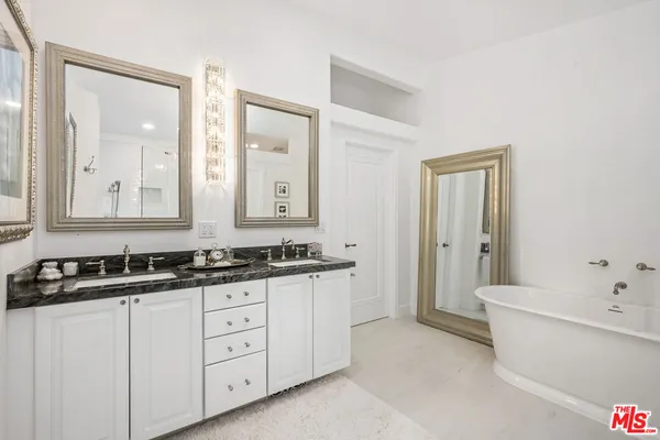 a spacious bathroom with a double vanity sink a mirror and a bathtub