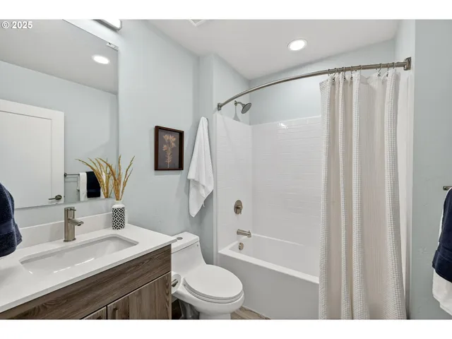 a bathroom with a granite countertop sink a toilet a mirror a shower and a bathtub