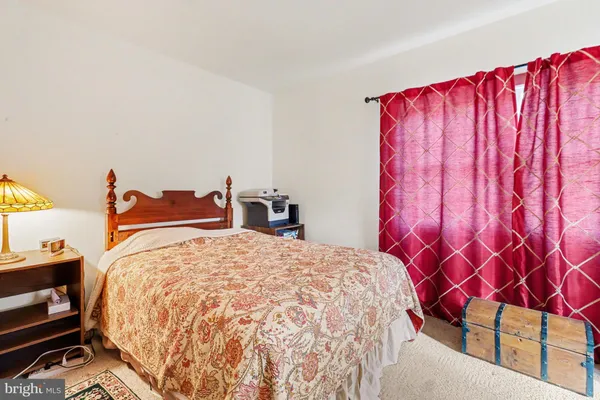 a bed sitting in a bedroom next to a lamp and a large window