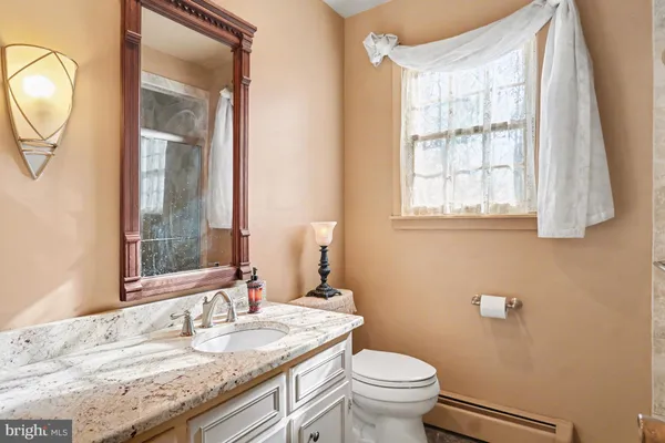 a bathroom with a granite countertop toilet a sink and a mirror