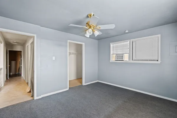 an empty room with a chandelier fan and windows
