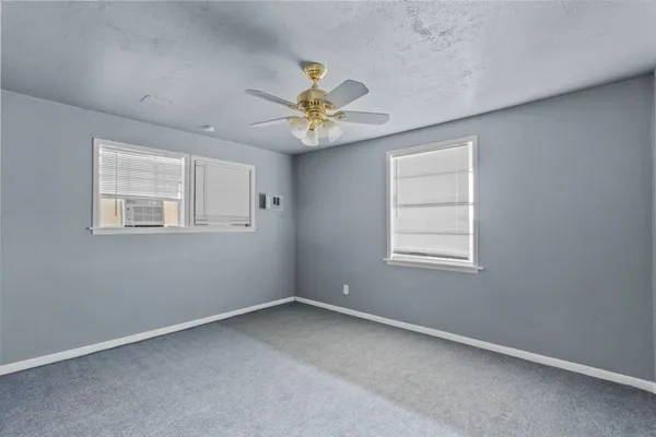 an empty room with windows and chandelier fan