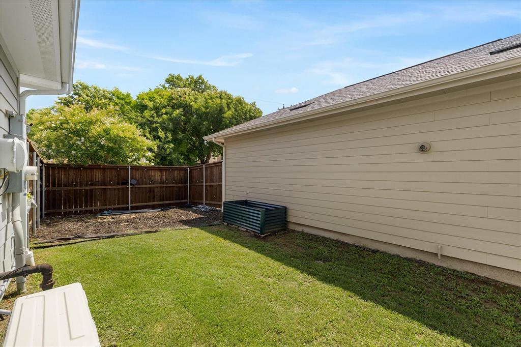9224 Lamar Street Rowlett, TX 75089 - Photo 22 of 27 Fenced backyard with manicured lawn and a privacy fence, showcasing exterior siding and a pitched roofline