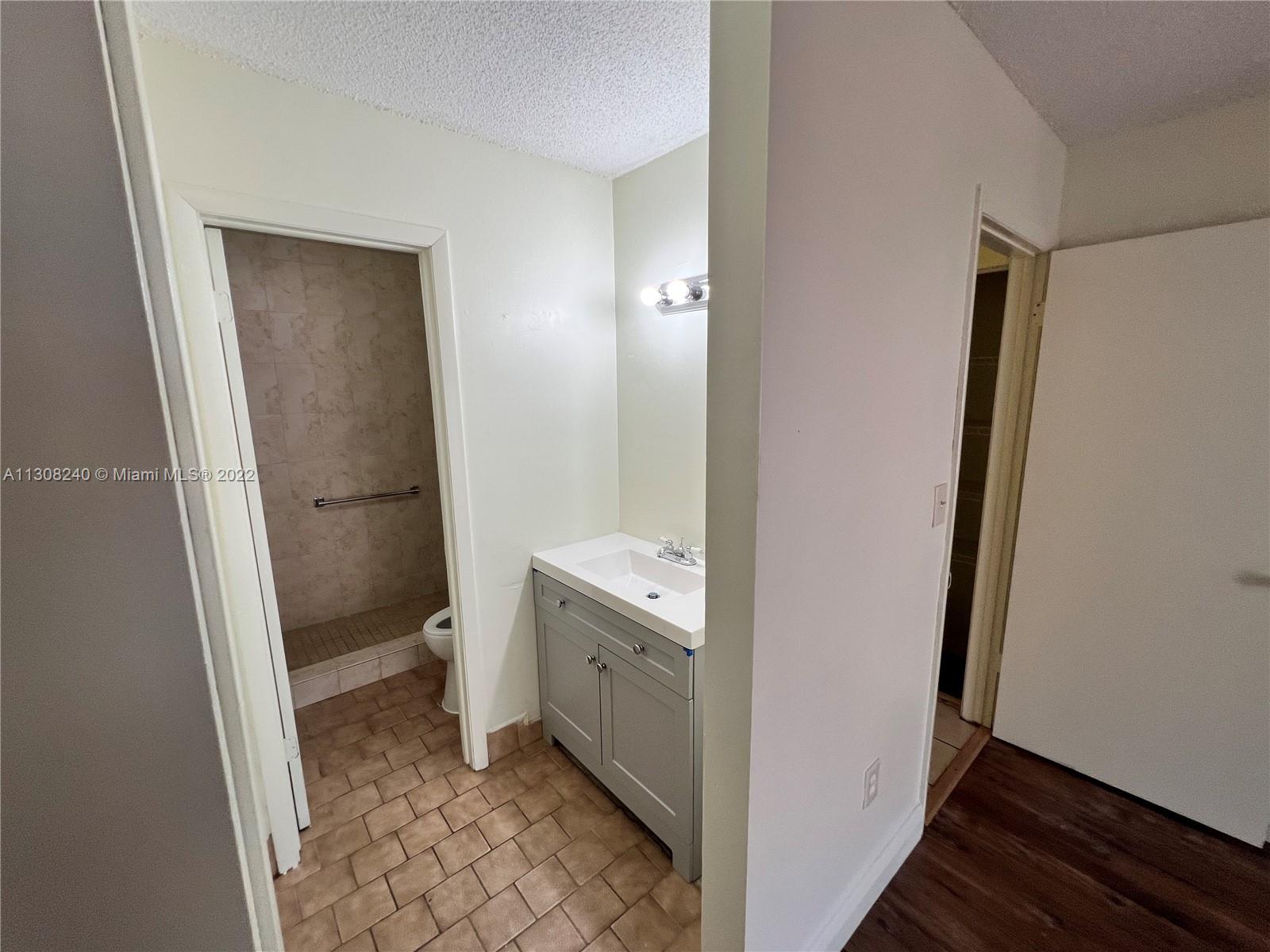 9630 Southwest 152nd Avenue, Unit 34 Miami, FL 33196 - Photo 7 of 13 a bathroom with a granite countertop sink toilet and shower