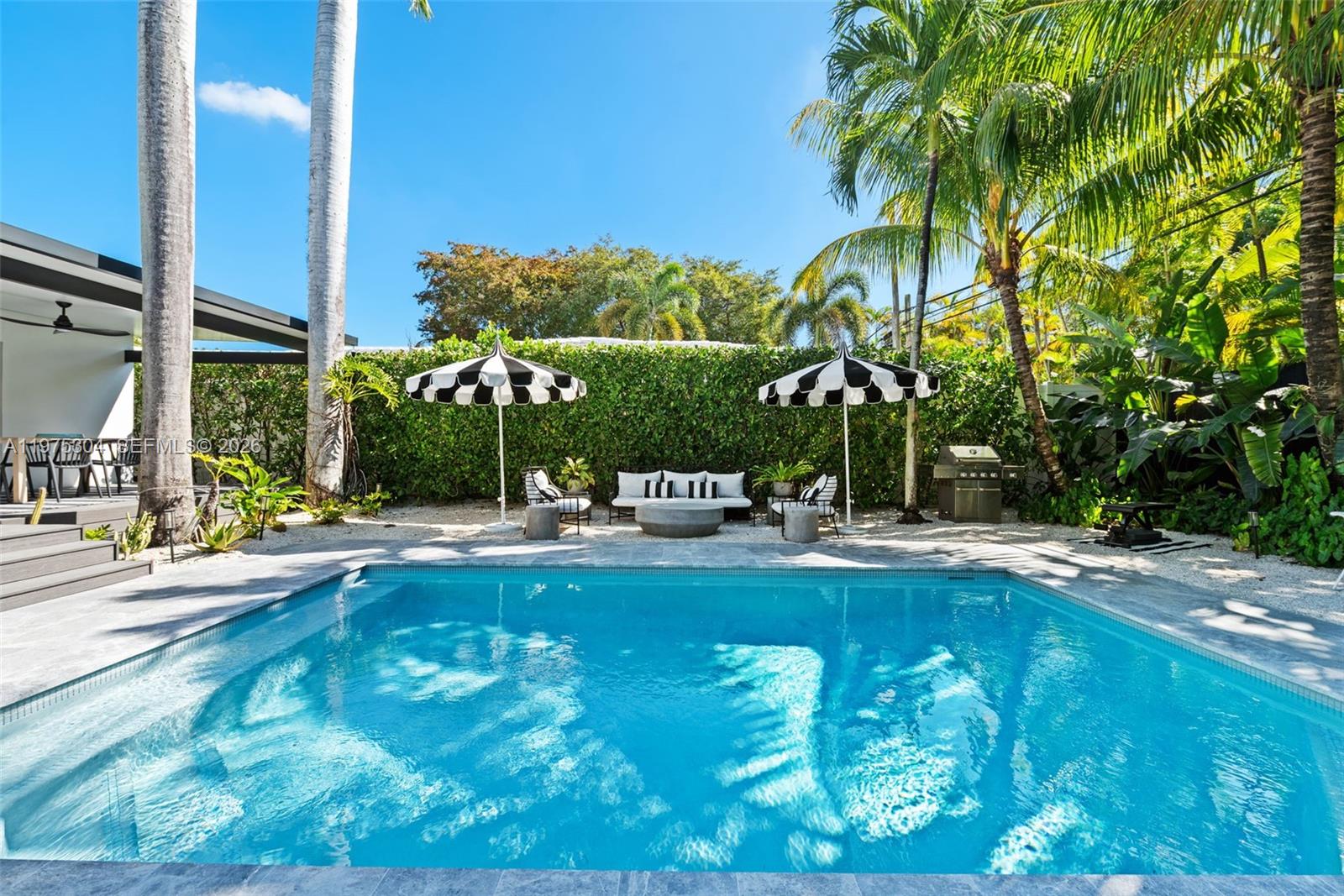 a view of a swimming pool with lawn chairs and plants