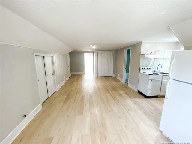 a view of a kitchen with a sink refrigerator and wooden floor