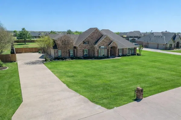 a view of a big house with a big yard and large trees