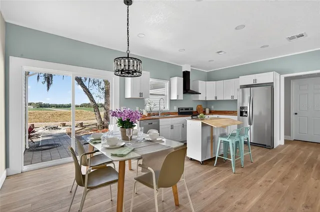 a kitchen with stainless steel appliances granite countertop a dining table chairs and white cabinets