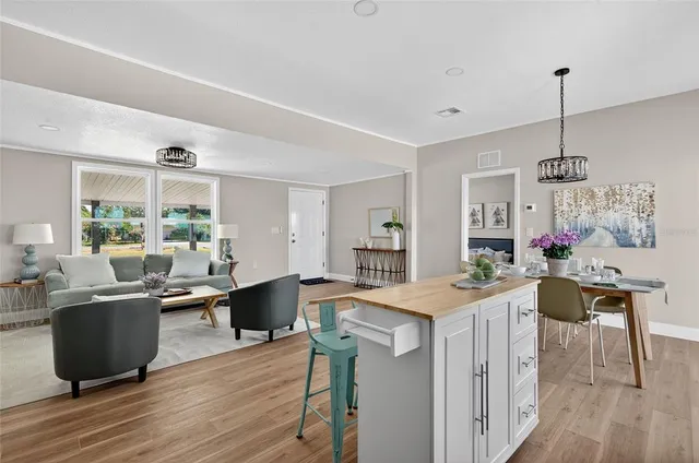 a kitchen with a stove a sink dishwasher a dining table and chairs with wooden floor