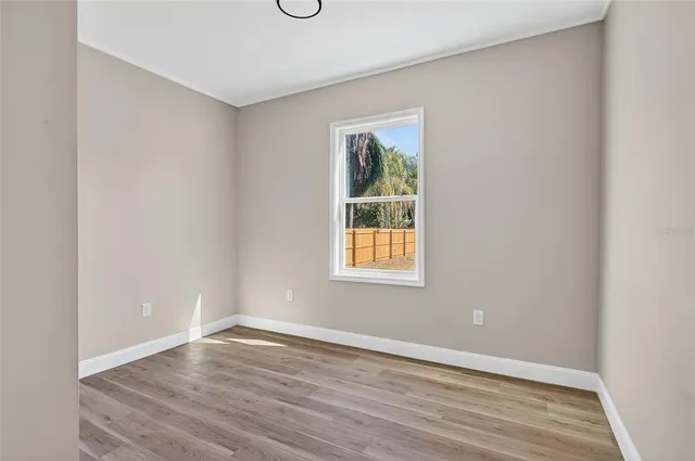 a view of an empty room with wooden floor and a window