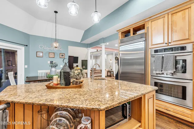 a kitchen with stainless steel appliances granite countertop a stove top oven a sink dishwasher a dining table and chairs with wooden floor