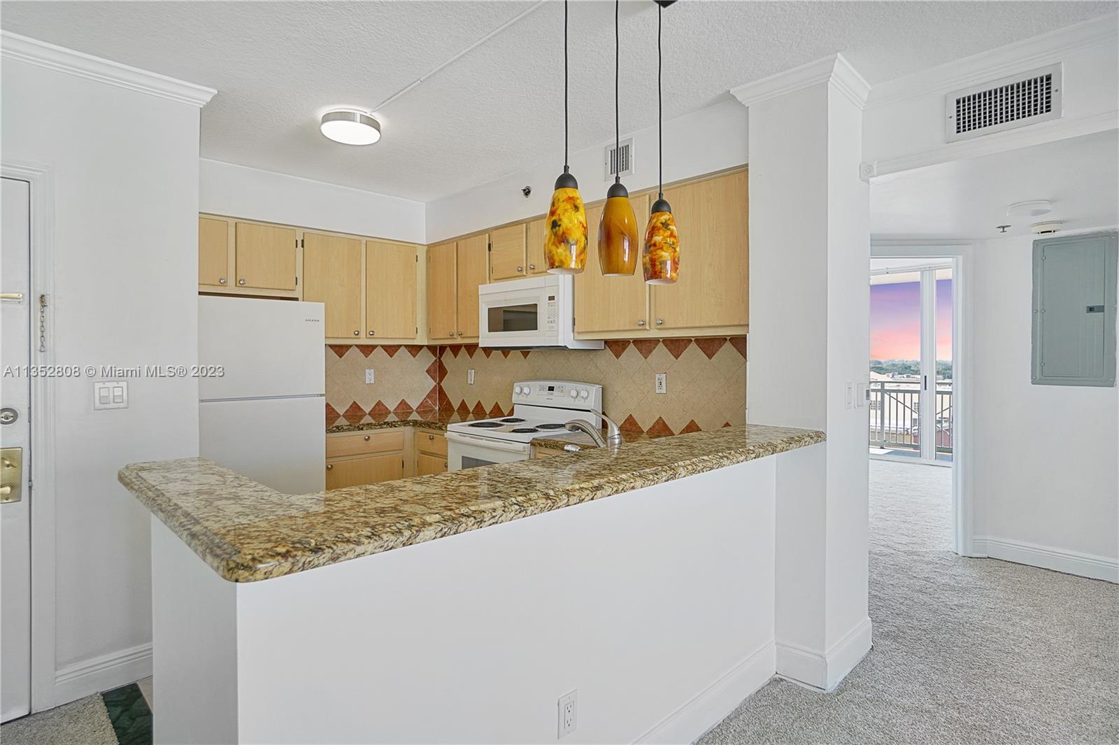 2665 Southwest 37th Avenue, Unit 914 Miami, FL 33133 - Photo 6 of 30 a kitchen with kitchen island granite countertop a sink a counter top space and cabinets