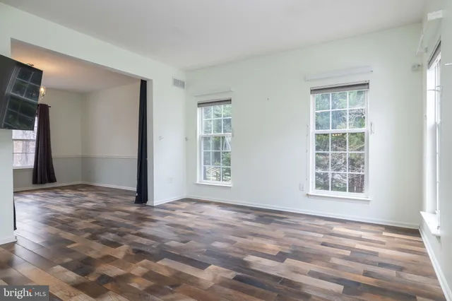 a view of an empty room with window and wooden floor