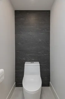 a white toilet sitting in a bathroom next to a wooden wall