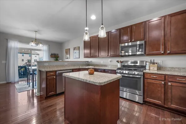 a kitchen with stainless steel appliances granite countertop wooden cabinets a refrigerator and a sink
