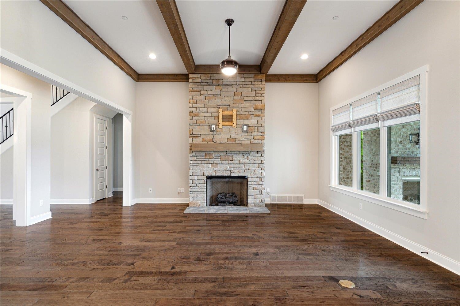 680 Magnolia Lane Piperton, TN 38017 - Photo 11 of 40 Unfurnished living room featuring beamed ceiling, wood finished floors, a stone fireplace, and baseboards