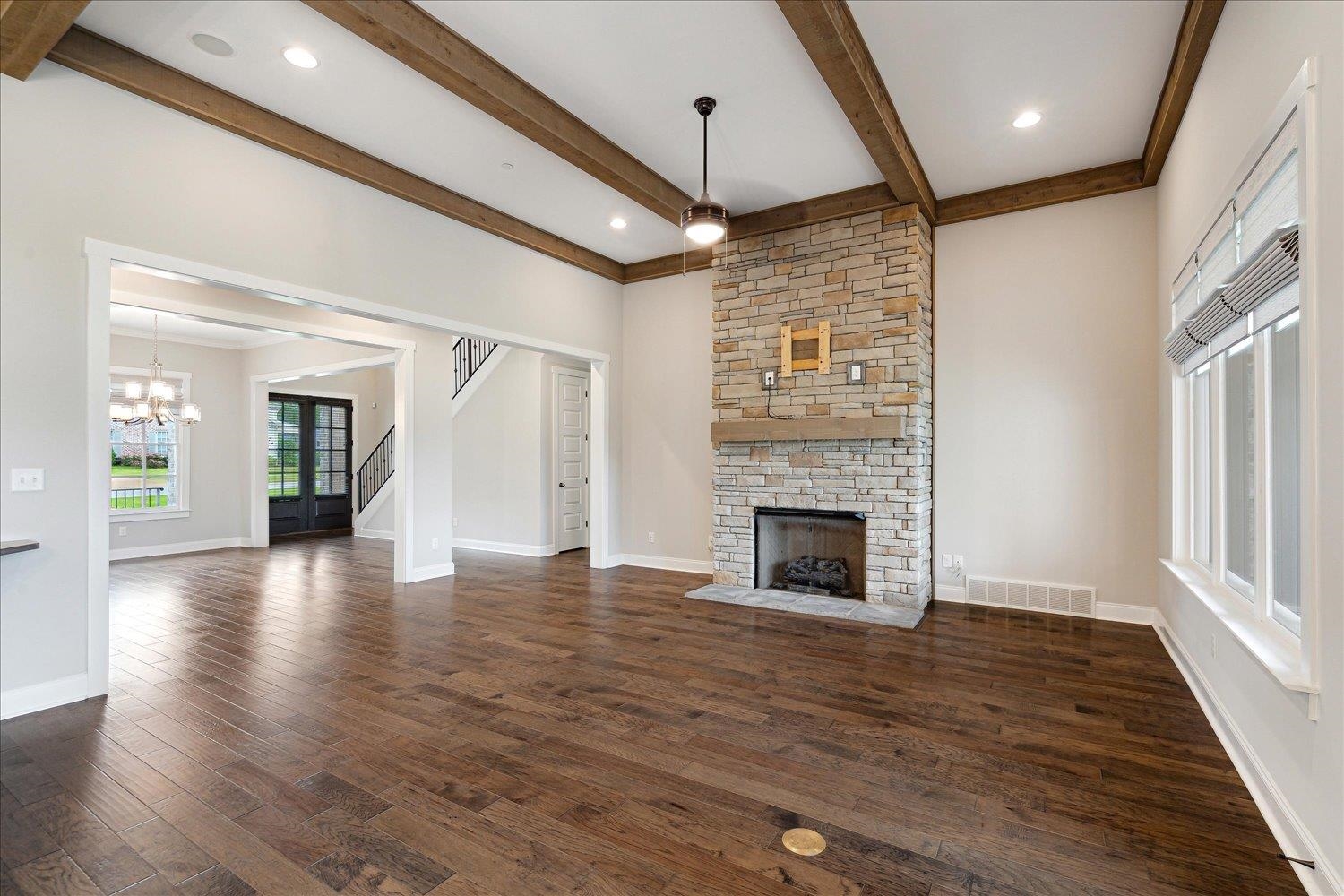 680 Magnolia Lane Piperton, TN 38017 - Photo 13 of 40 Unfurnished living room featuring a fireplace, beam ceiling, dark wood finished floors, a chandelier, and baseboards