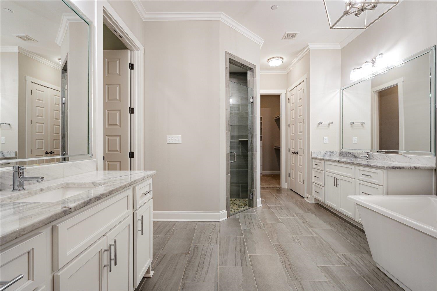 680 Magnolia Lane Piperton, TN 38017 - Photo 16 of 40 Bathroom with crown molding, a stall shower, two vanities, a chandelier, and a freestanding bath