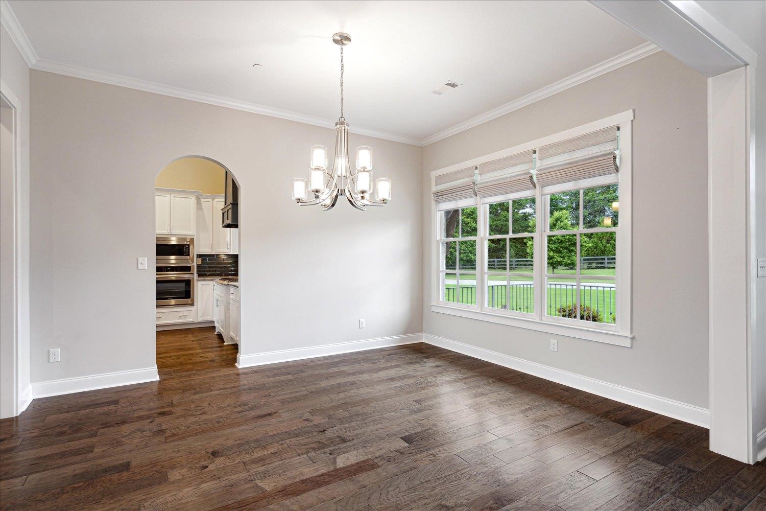 680 Magnolia Lane Piperton, TN 38017 - Photo 24 of 40 Unfurnished dining area featuring ornamental molding, a chandelier, arched walkways, dark wood-style floors, and baseboards