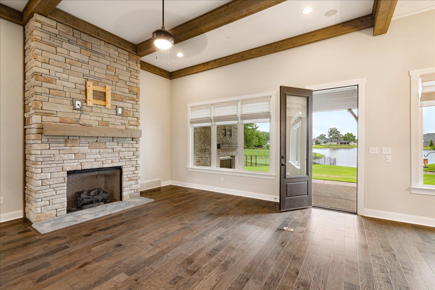 680 Magnolia Lane Piperton, TN 38017 - Photo 25 of 40 Unfurnished living room featuring beamed ceiling, wood finished floors, a water view, ceiling fan, and a fireplace