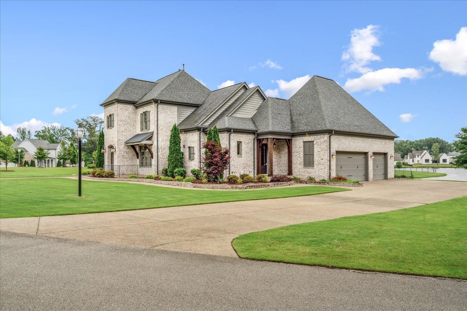 680 Magnolia Lane Piperton, TN 38017 - Photo 39 of 40 French country style house with brick siding, a front yard, an attached garage, driveway, and roof with shingles