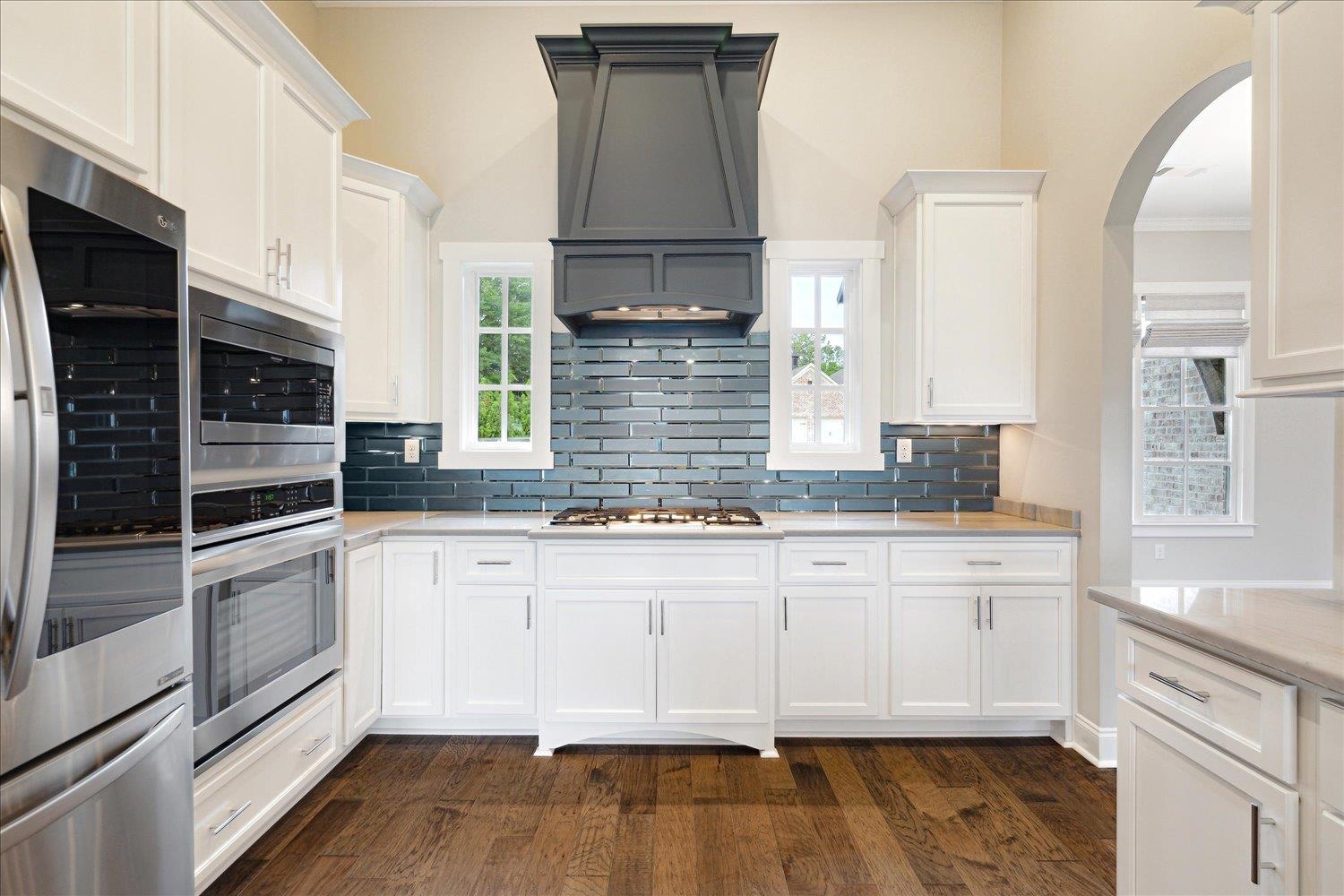 680 Magnolia Lane Piperton, TN 38017 - Photo 7 of 40 Kitchen with stainless steel appliances, custom exhaust hood, arched walkways, dark wood-type flooring, and tasteful backsplash