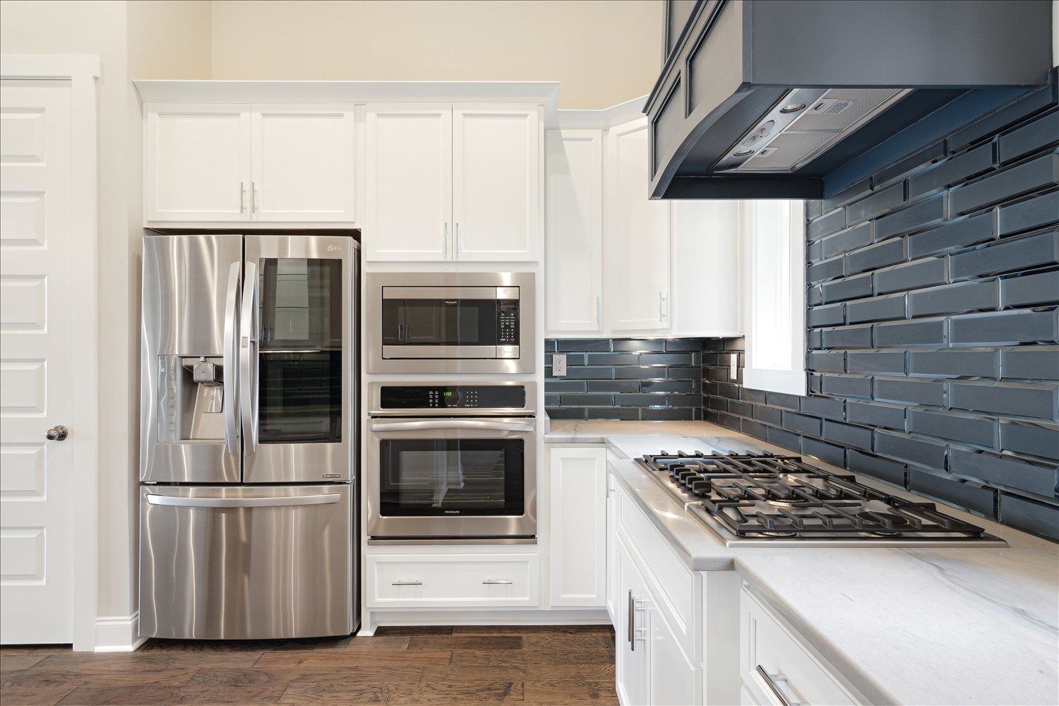 680 Magnolia Lane Piperton, TN 38017 - Photo 10 of 40 Kitchen featuring appliances with stainless steel finishes, ventilation hood, white cabinetry, and decorative backsplash