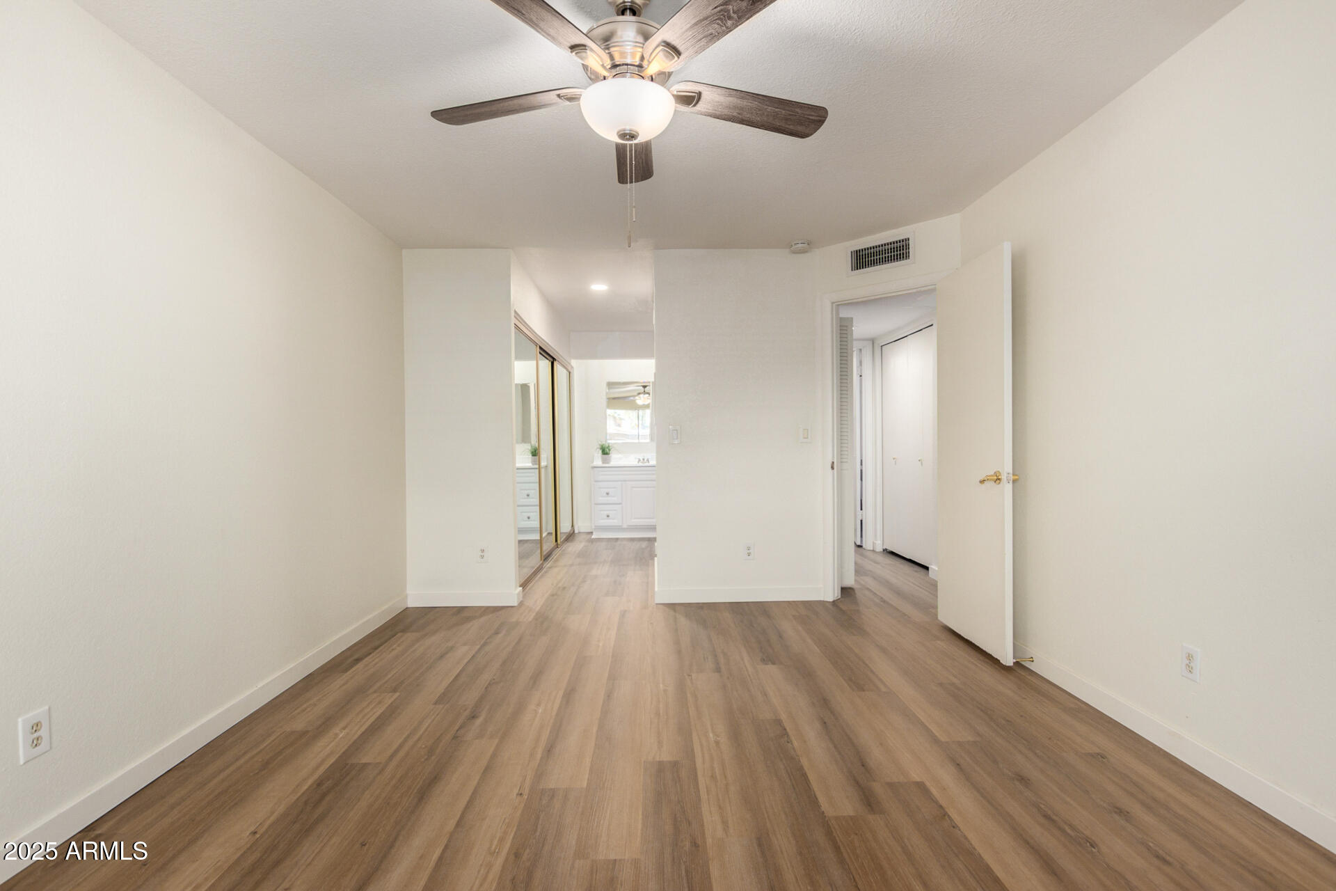 700 East Mesquite Circle, Unit L107 Tempe, AZ 85288 - Photo 12 of 26 an empty room with wooden floor a ceiling fan and closet