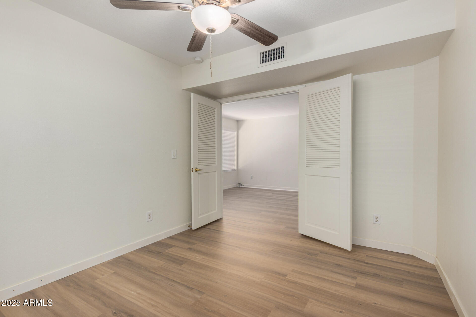 700 East Mesquite Circle, Unit L107 Tempe, AZ 85288 - Photo 18 of 26 an empty room with wooden floor chandelier fan and closet in a room
