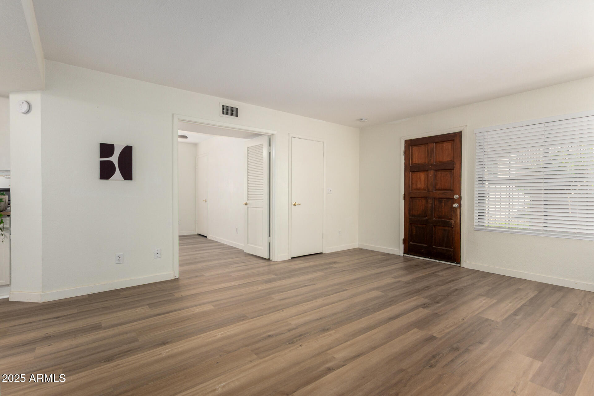 700 East Mesquite Circle, Unit L107 Tempe, AZ 85288 - Photo 4 of 26 an empty room with wooden floor and windows