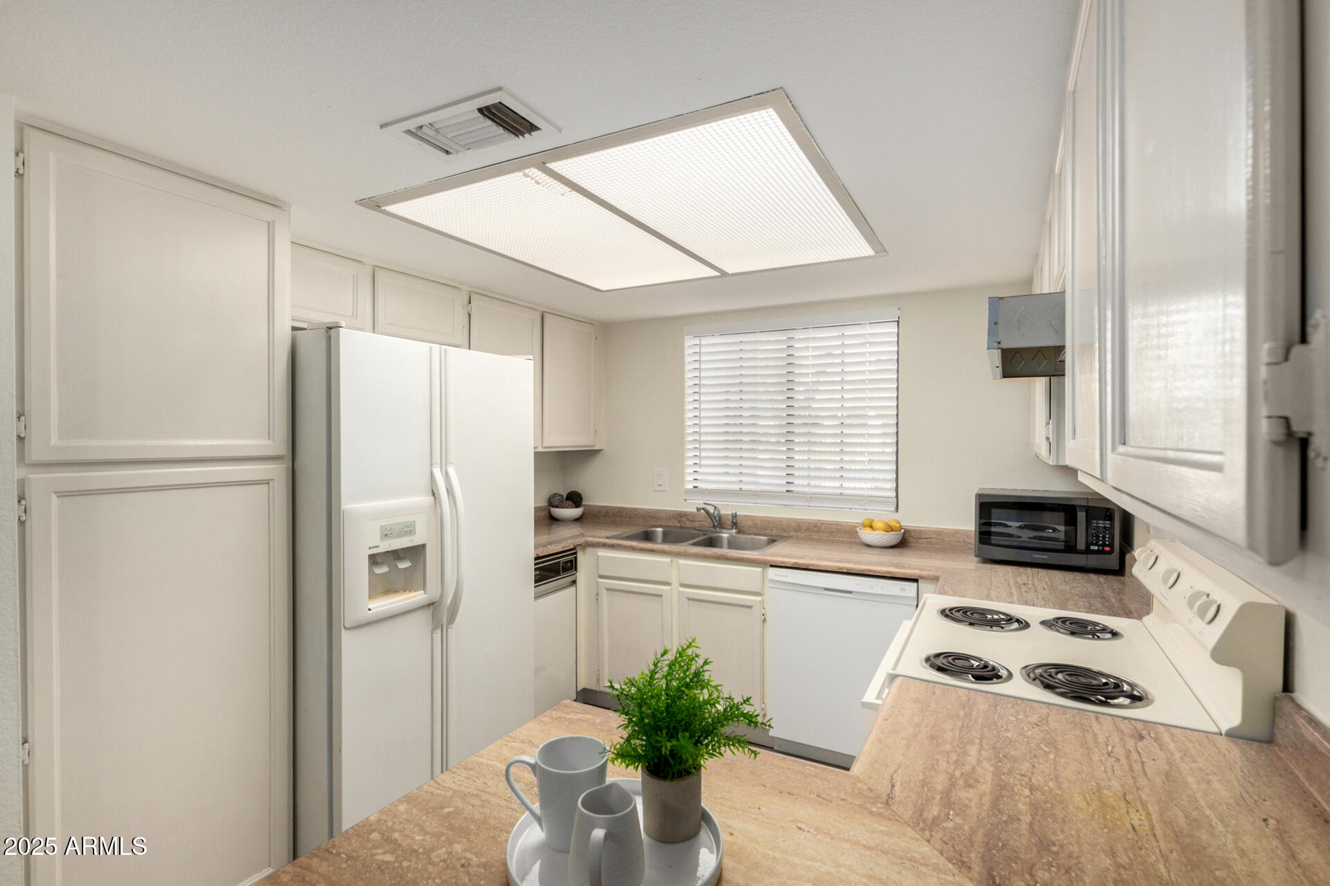 700 East Mesquite Circle, Unit L107 Tempe, AZ 85288 - Photo 7 of 26 a kitchen with a refrigerator a sink a stove and white cabinets