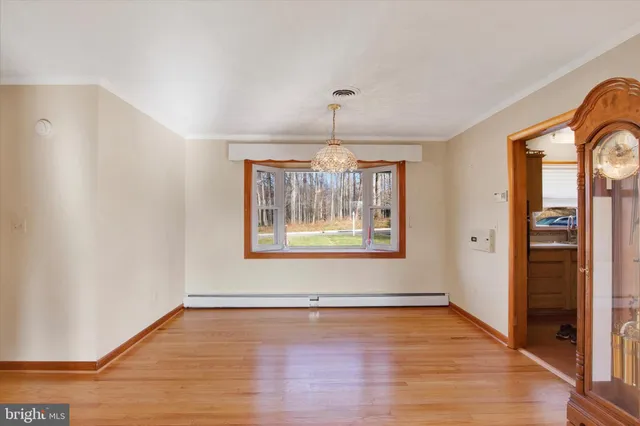 an empty room with wooden floor chandelier and windows