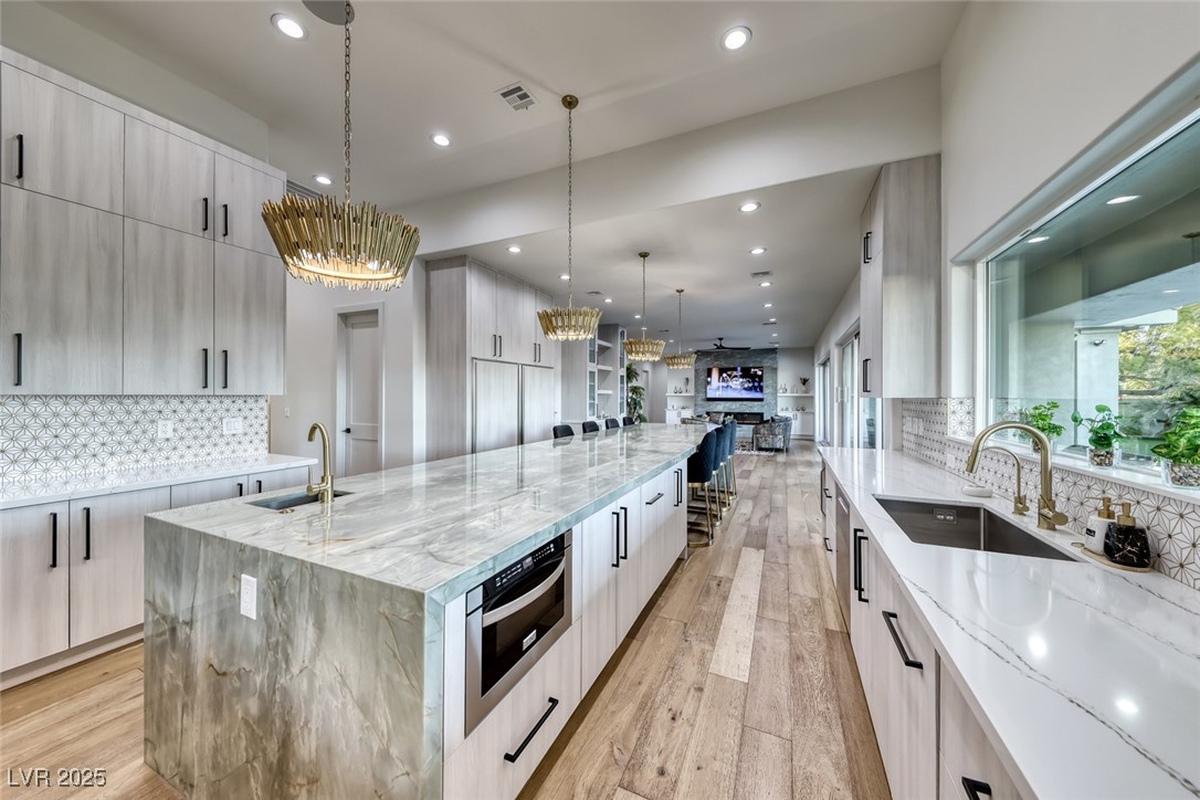 2309 Prometheus Court Henderson, NV 89074 - Photo 14 of 86 Kitchen with decorative backsplash, light stone counters, light wood-style flooring, and recessed lighting